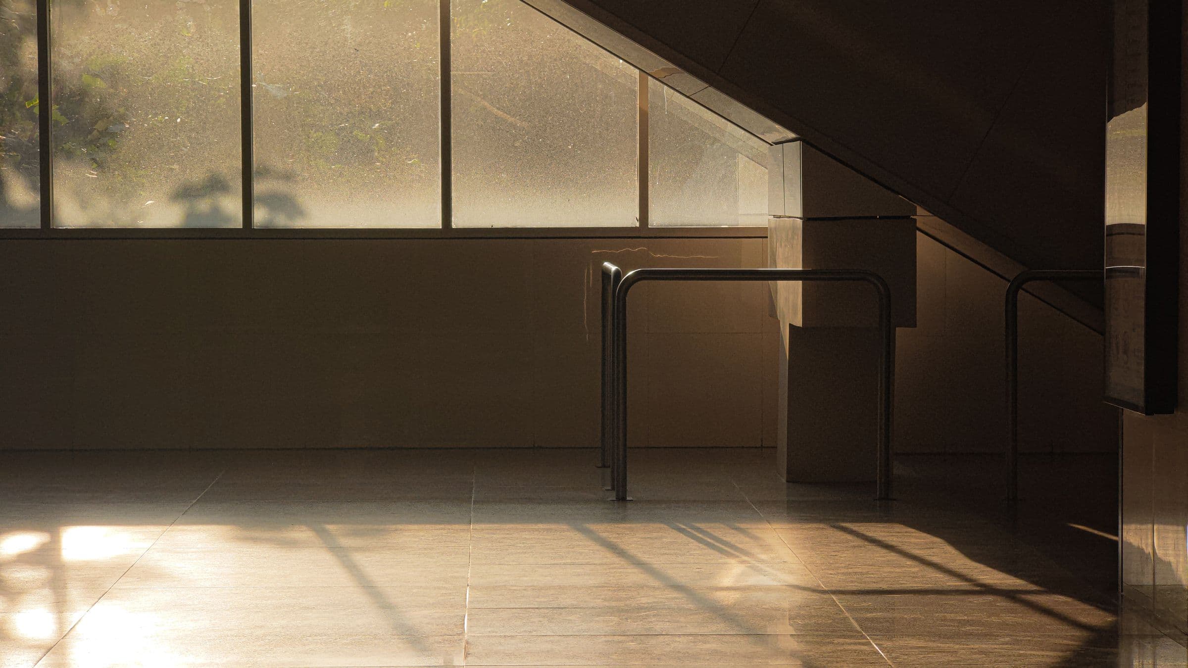 Low morning sun crossing the floor of an empty room through a long band of windows.